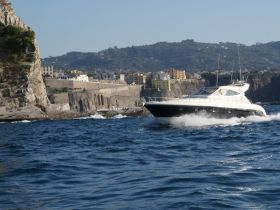 A sleek speedboat navigates the waters near a picturesque coastline, showcasing the beauty of the surrounding landscape.