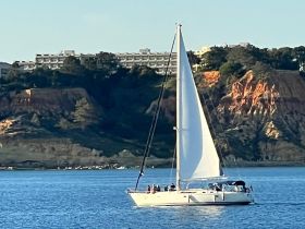 A beautiful sailboat glides through the water, showcasing a stunning coastline backdrop — perfect for sailing adventures and scenic views.