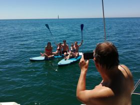 A group of friends enjoys paddleboarding in the open water, capturing fun moments under the sun — perfect for summer adventures on the water.