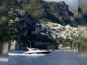 A sleek speedboat navigates the stunning coastline, showcasing the picturesque cliffs and colorful homes of the Amalfi Coast.