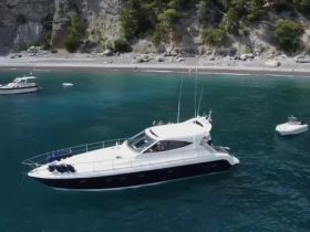 A stunning aerial view of a sleek yacht anchored in crystal-clear waters, surrounded by a picturesque coastline — perfect for luxury getaways and coastal exploration.