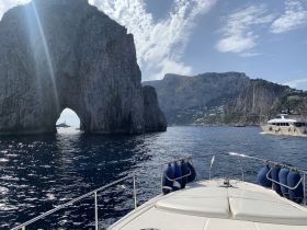 A stunning view of the iconic rock formations off the coast of Capri, with yachts navigating the serene waters — a perfect representation of the breathtaking scenery in this Mediterranean paradise.