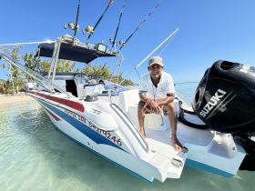 A smiling captain sits on the edge of a fishing boat, ready for an adventure on the water. Perfect for fishing trips and exploring the beautiful coastline.