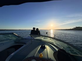 A couple enjoys a romantic moment on a boat at sunset, creating a picturesque scene perfect for intimate outings on the water.