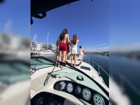 A group of friends enjoys a sunny day on the boat, celebrating together with stunning marina views in the background — perfect for memorable outings and gatherings.