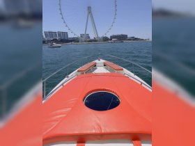 A stunning view from the front of a yacht, showcasing the vibrant orange seating and the iconic Ferris wheel in the background — perfect for a day out on the water.