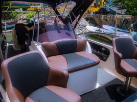 Interior view of a boat's seating area, showcasing comfortable helm and lounge spaces, perfect for relaxing while on the water.