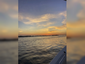 A serene sunset view from a boat, showcasing the tranquil waters and vibrant sky — perfect for evening cruises and relaxation on the water.