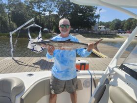 A proud angler displays his impressive catch of the day while standing on a boat, showcasing the thrill of fishing adventures.