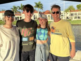 A cheerful group of friends poses for a photo on a boat, enjoying a sunny day on the water — perfect for family outings or celebrations.