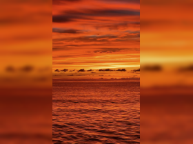A stunning sunset over the ocean, showcasing vibrant orange and red hues reflecting on the water's surface.