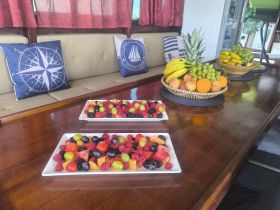 A beautifully arranged display of fresh fruit and snacks on a boat's dining table, perfect for guests to enjoy while cruising the waters.