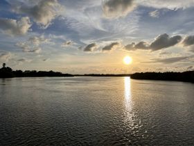 A stunning sunset over a tranquil waterway, reflecting golden hues on the surface — perfect for capturing the beauty of nature during a boating adventure.