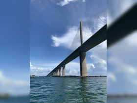A view of a bridge over water, captured from below, showcasing its architectural structure against a blue sky.