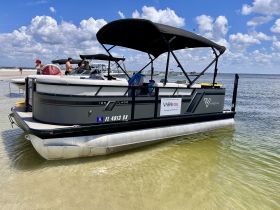 A lively scene featuring a pontoon boat at the beach with guests enjoying the sun and water activities, perfect for summer outings.