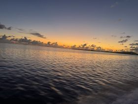 A stunning sunset over calm waters, capturing the serene beauty of the coastline — perfect for romantic evening cruises or peaceful reflections on the water.