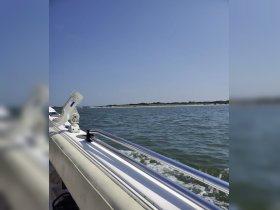 A side view of a boat cruising through calm waters, showcasing the sleek design and tranquil surroundings — perfect for a day on the water.