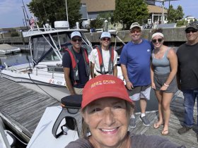 A cheerful group poses for a selfie on the dock next to their boat, capturing a fun day out on the water with friends and family.
