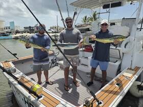 Three anglers proudly display their catch of the day aboard a fishing boat, showcasing a successful fishing trip in beautiful waters.