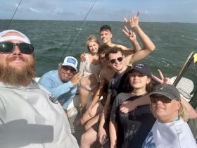 A lively group of friends enjoys a fishing trip, capturing the fun and camaraderie aboard the boat — perfect for adventure seekers and fishing enthusiasts.