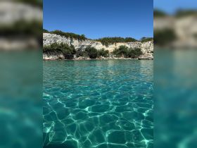 A stunning view of clear turquoise waters lapping against a rocky coastline, perfect for showcasing the natural beauty of the area.