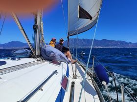 A couple enjoys a sailing adventure on a sunny day, with stunning mountain views in the background — perfect for romantic getaways or scenic tours.