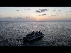 A group celebrates at sunset aboard a pontoon boat, creating a picturesque moment on the water — perfect for unforgettable gatherings and sunset cruises.