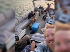 A lively group enjoys a fun moment aboard a pontoon boat, showcasing smiles and excitement as they celebrate together on the water.
