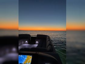 A serene view of the interior seating area of a boat, illuminated softly as the sun sets over the water, creating a perfect ambiance for evening cruises.