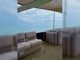A cozy lounge area inside a boat, featuring comfortable seating and a serene view of the calm waters, perfect for relaxing during a day on the water.