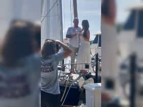 A couple celebrates with champagne on the deck of a boat, capturing a memorable moment with a photographer — perfect for wedding or engagement celebrations.