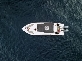 Aerial view of a fishing boat with people on board, enjoying a day on the ocean — perfect for fishing enthusiasts and family outings.