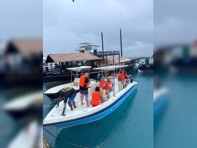 A lively group prepares to embark on an adventure aboard a boat, all wearing life jackets for safety — perfect for fun-filled excursions on the water.