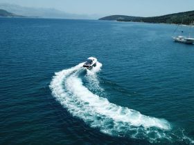 A stunning aerial view of a speedboat cruising through crystal-clear waters, showcasing the beauty of a summer day on the sea.