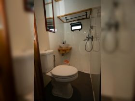 Interior view of a boat bathroom featuring a toilet, sink, and shower, designed for comfort and convenience while at sea.