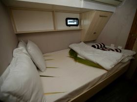 Cozy cabin interior featuring a neatly made bed with plush pillows and decorative touches, perfect for relaxing on a boat.