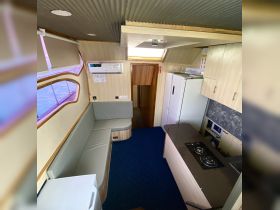 Interior view of a boat's cabin featuring comfortable seating and a well-equipped kitchen area, perfect for relaxing and dining while on the water.
