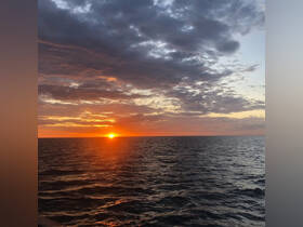 A stunning sunset over the ocean, showcasing vibrant colors reflecting on the water's surface — perfect for serene evening boat cruises.