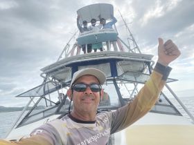 A joyful group of friends celebrates aboard a fishing boat, showcasing camaraderie and adventure on the water.