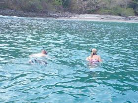 A couple enjoys snorkeling in crystal-clear waters, exploring the vibrant marine life near a secluded beach — a perfect adventure for water enthusiasts.