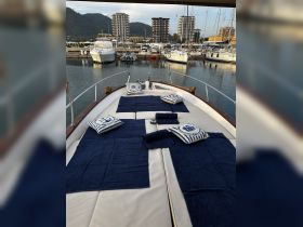 A cozy lounge area on a boat, featuring navy towels and decorative pillows, perfect for relaxation while enjoying the marina views.