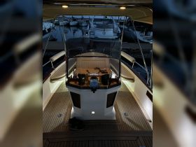 A cozy view of the helm area inside a boat, illuminated at night, showcasing the console and seating — perfect for evening cruises or relaxing on the water.