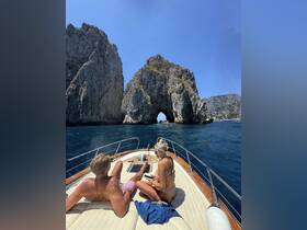 A couple relaxes on the deck of a boat, enjoying the stunning rock formations in the background — a perfect moment for a romantic getaway on the water.