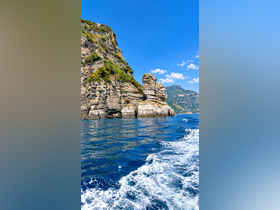 A stunning view of dramatic rock formations along a beautiful coastline, showcasing the vibrant blue waters and clear skies — perfect for scenic boat tours.