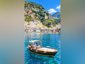 A group enjoys a scenic boat ride along the stunning Amalfi Coast, with picturesque cliffs and charming villages in the backdrop — a perfect getaway for exploring coastal beauty.