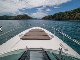 A stunning view from the front of a yacht cruising through calm waters, surrounded by lush green hills — perfect for scenic boating adventures.