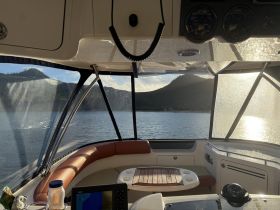 A cozy interior view of a boat's helm and seating area, showcasing the inviting space perfect for relaxation while enjoying scenic water views.