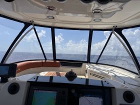 A view of the helm inside a boat, showcasing the console and seating area with a clear view of the ocean ahead — perfect for navigation and relaxation.