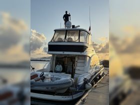 A man gives a thumbs up from the top of a boat while another man relaxes on the deck, capturing a moment of joy during a beautiful sunset.