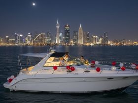 A couple enjoys a romantic evening on a beautifully decorated yacht against the stunning backdrop of a city skyline at night, perfect for special celebrations.